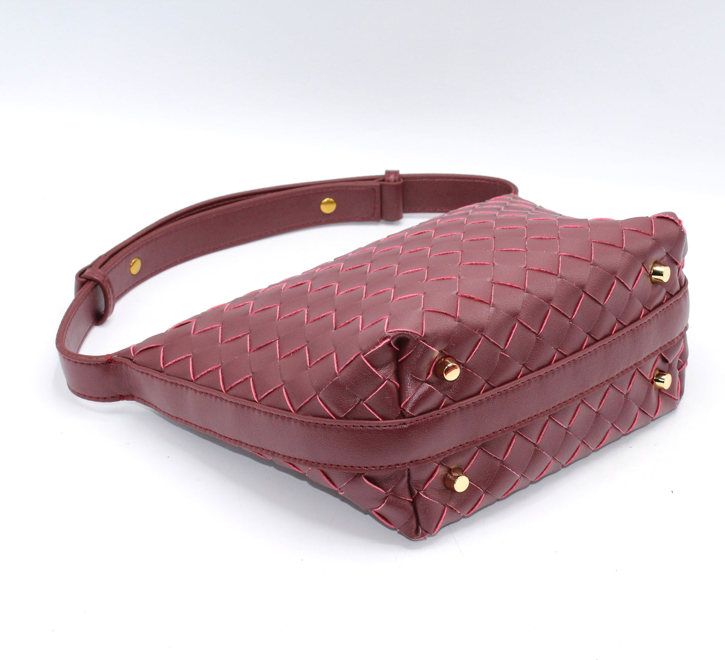 Genuine leather woven boxed pouch bag in burgundy with gold studs and a long shoulder strap.