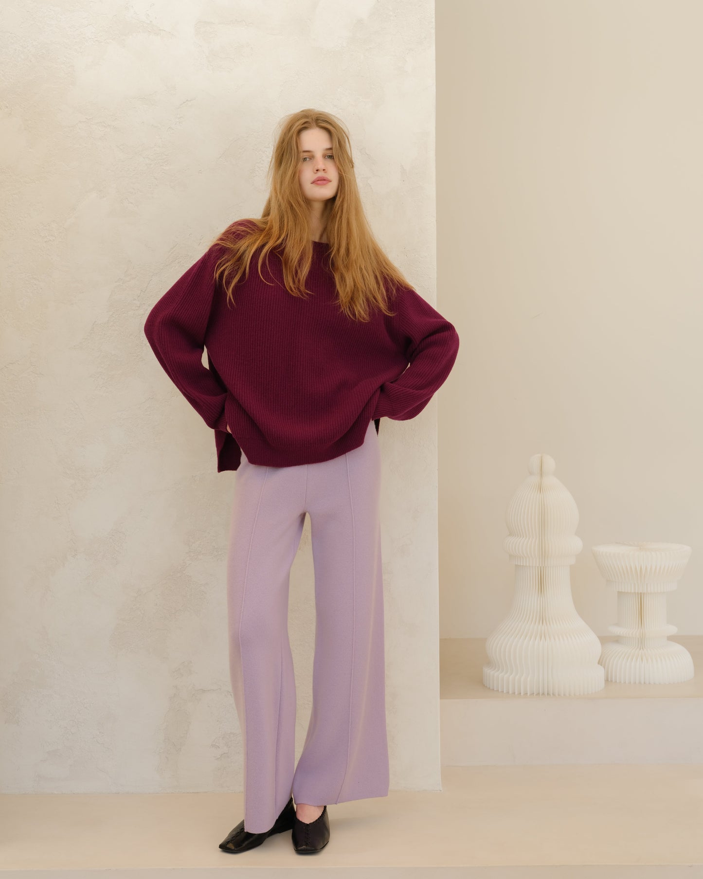 Model wearing burgundy Cashmere Mix Crewneck Ribbed Sweater with Lateral Slits over lavender wide-leg pants, hands on hips.