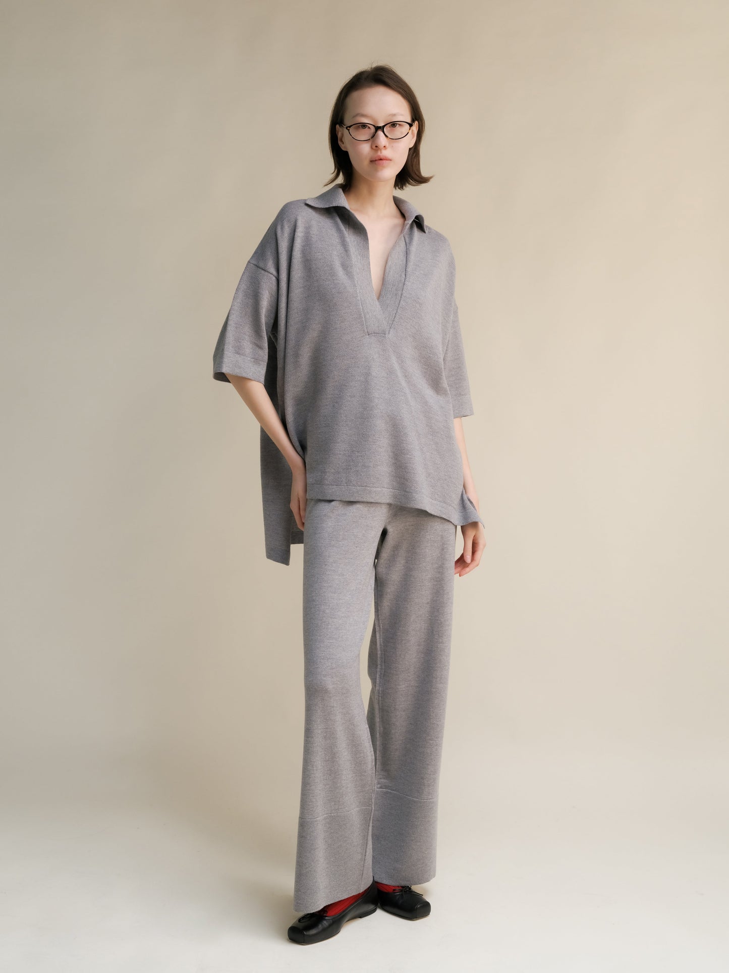 Model wearing grey oversized merino wool maxi polo with a collared neckline and matching wide-leg pants.