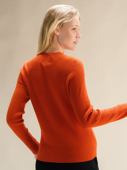 Back view of a bright orange ribbed cashmere mix mock neck sweater on a model.