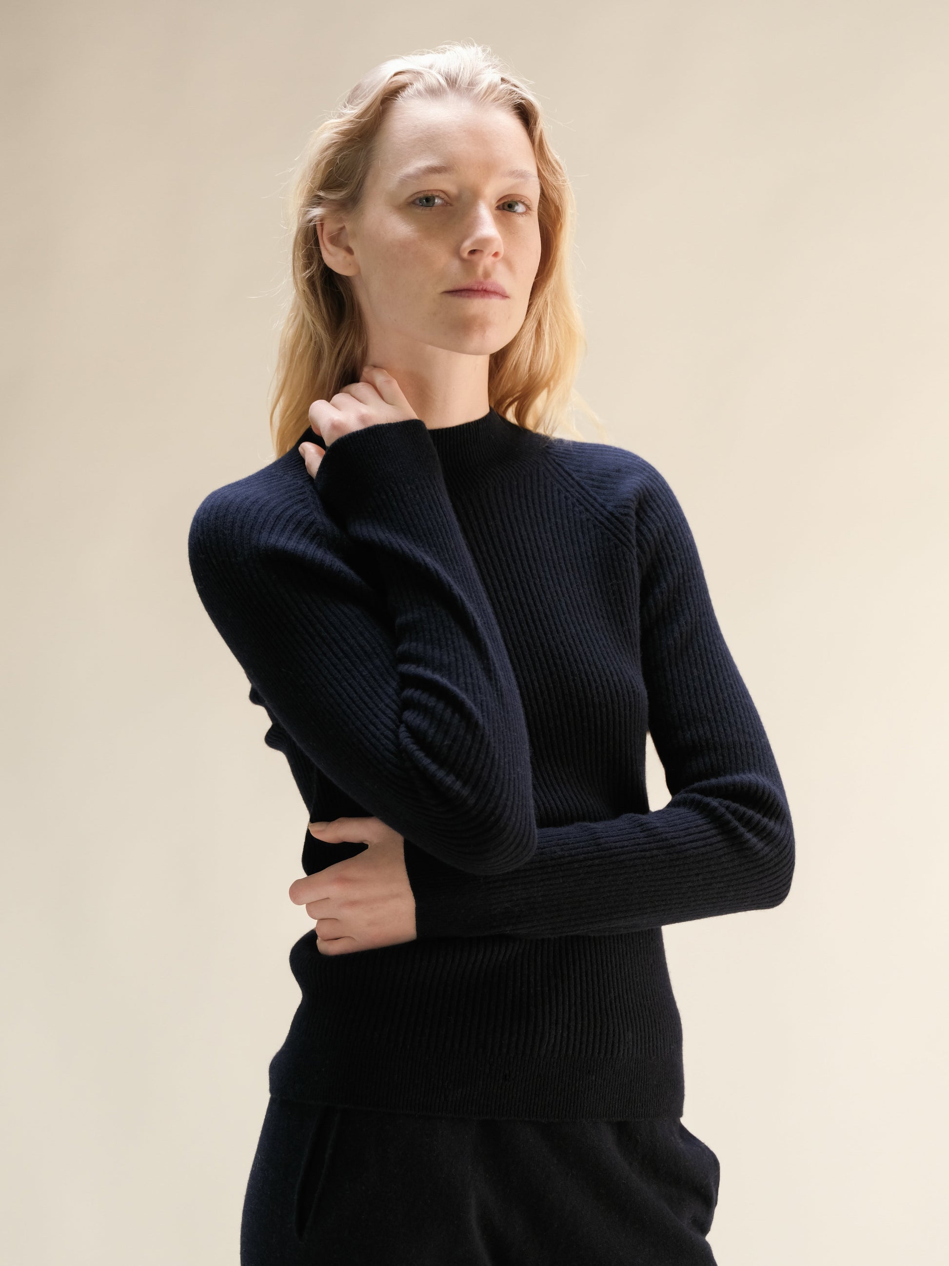 Model wearing navy ribbed cashmere mix mock neck sweater with long sleeves