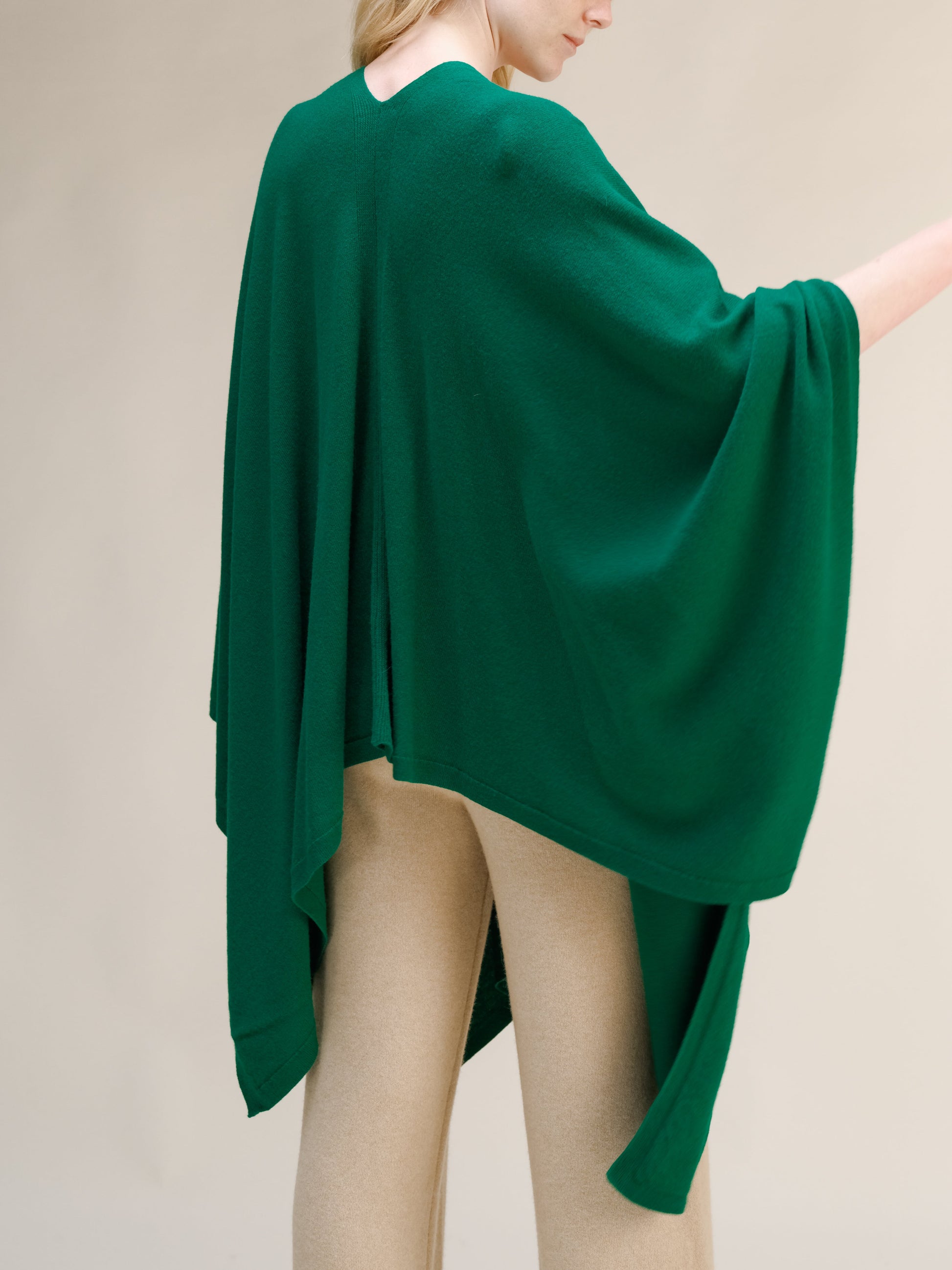 Green cashmere mix maxi cape draped over a model from the back, with beige pants visible.