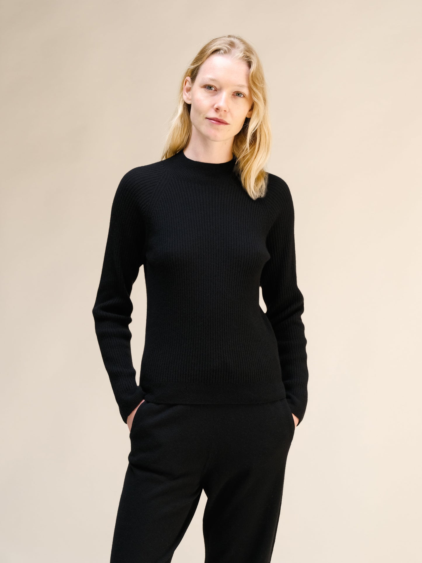 Model wearing black ribbed mock neck sweater with a 3D knit texture