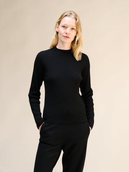 Model wearing black ribbed mock neck sweater with a 3D knit texture