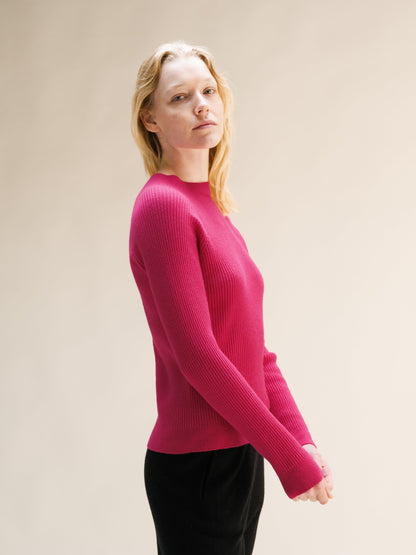 Side view of vibrant pink ribbed mock neck sweater.