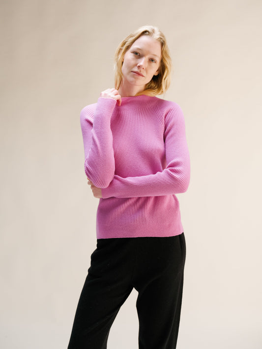 Model wearing pink ribbed mock neck sweater with soft knit texture