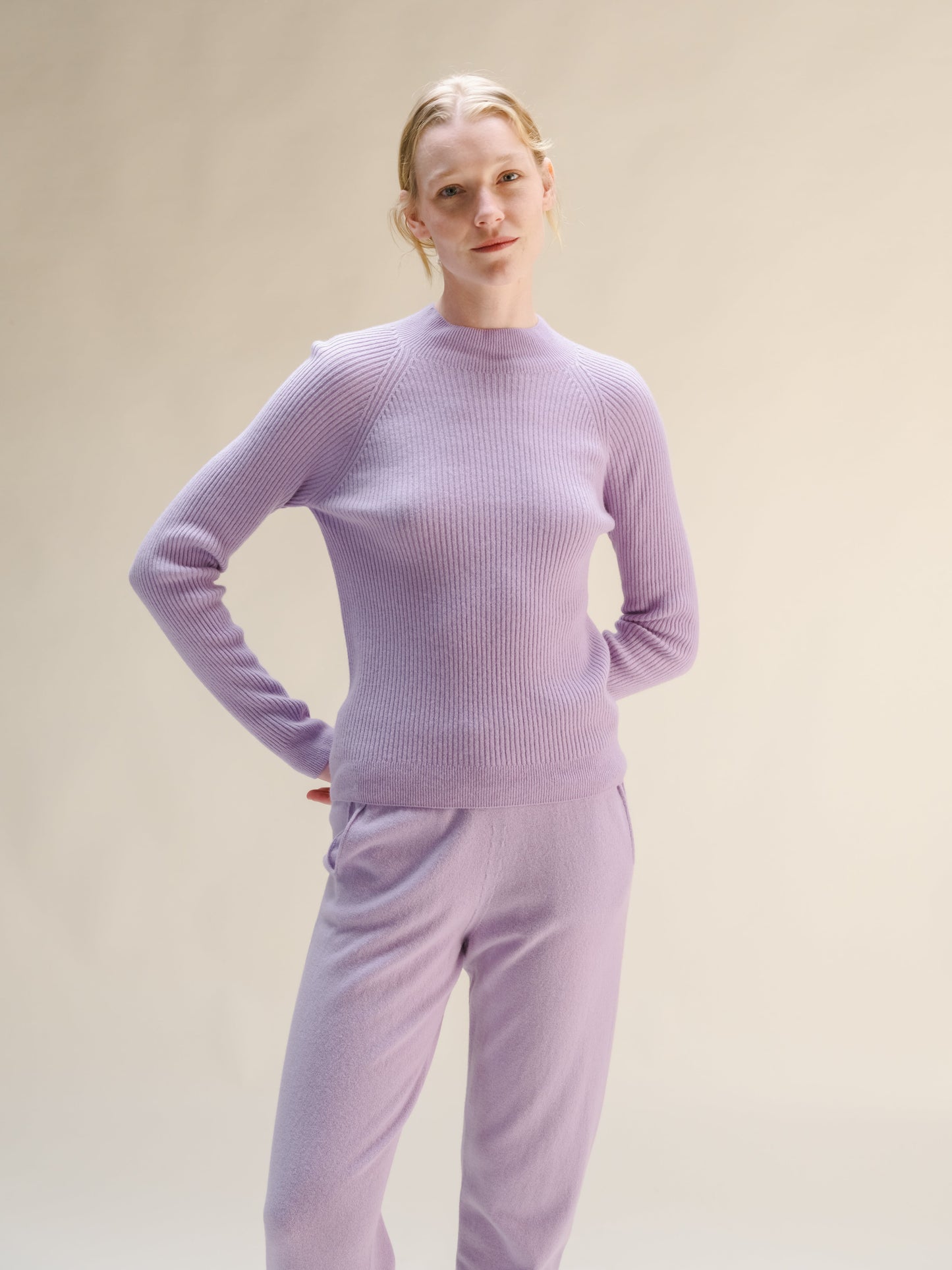 Woman wearing a lilac ribbed mock neck sweater with matching knit pants