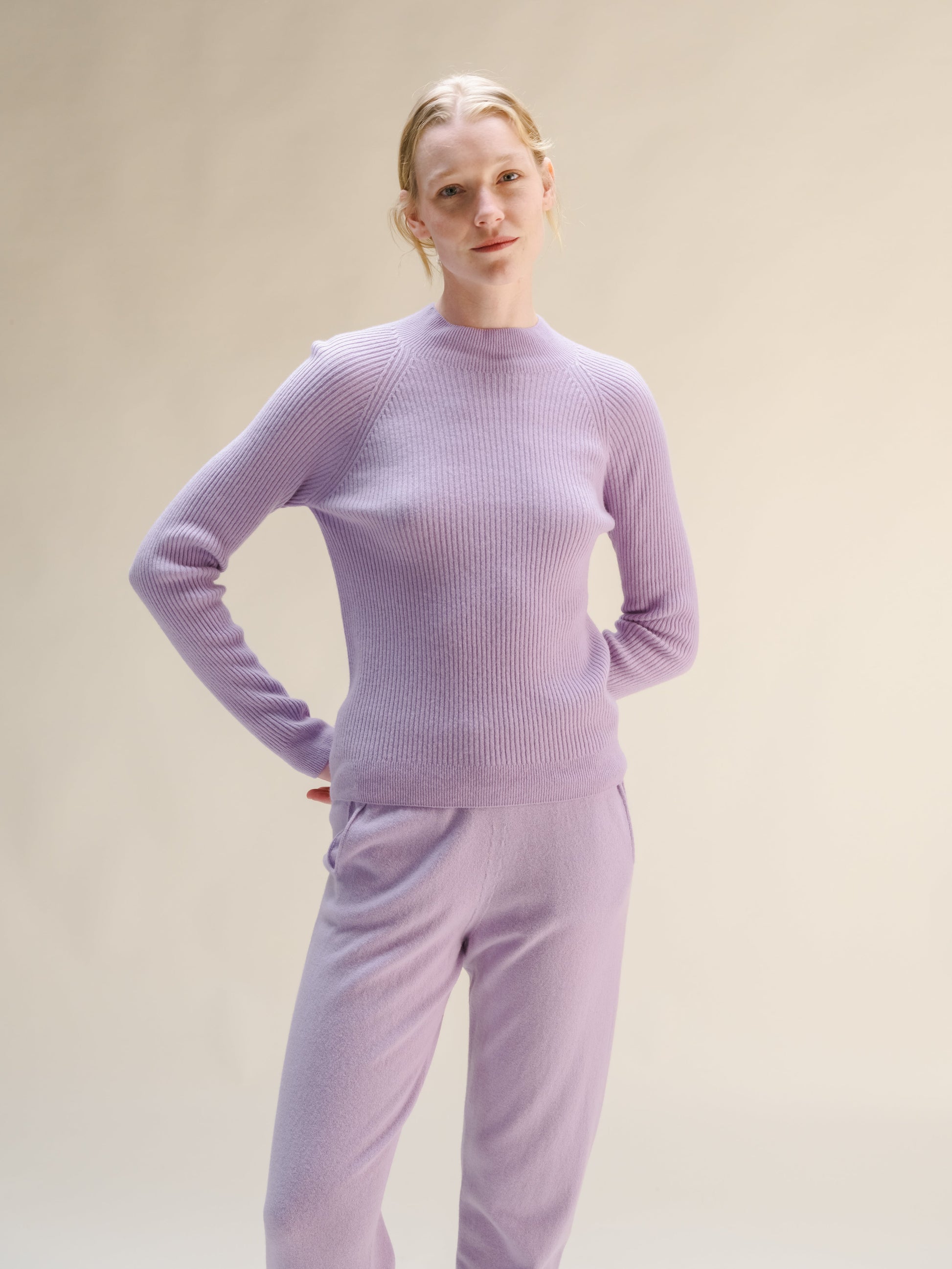 Woman wearing a lilac ribbed mock neck sweater with matching knit pants