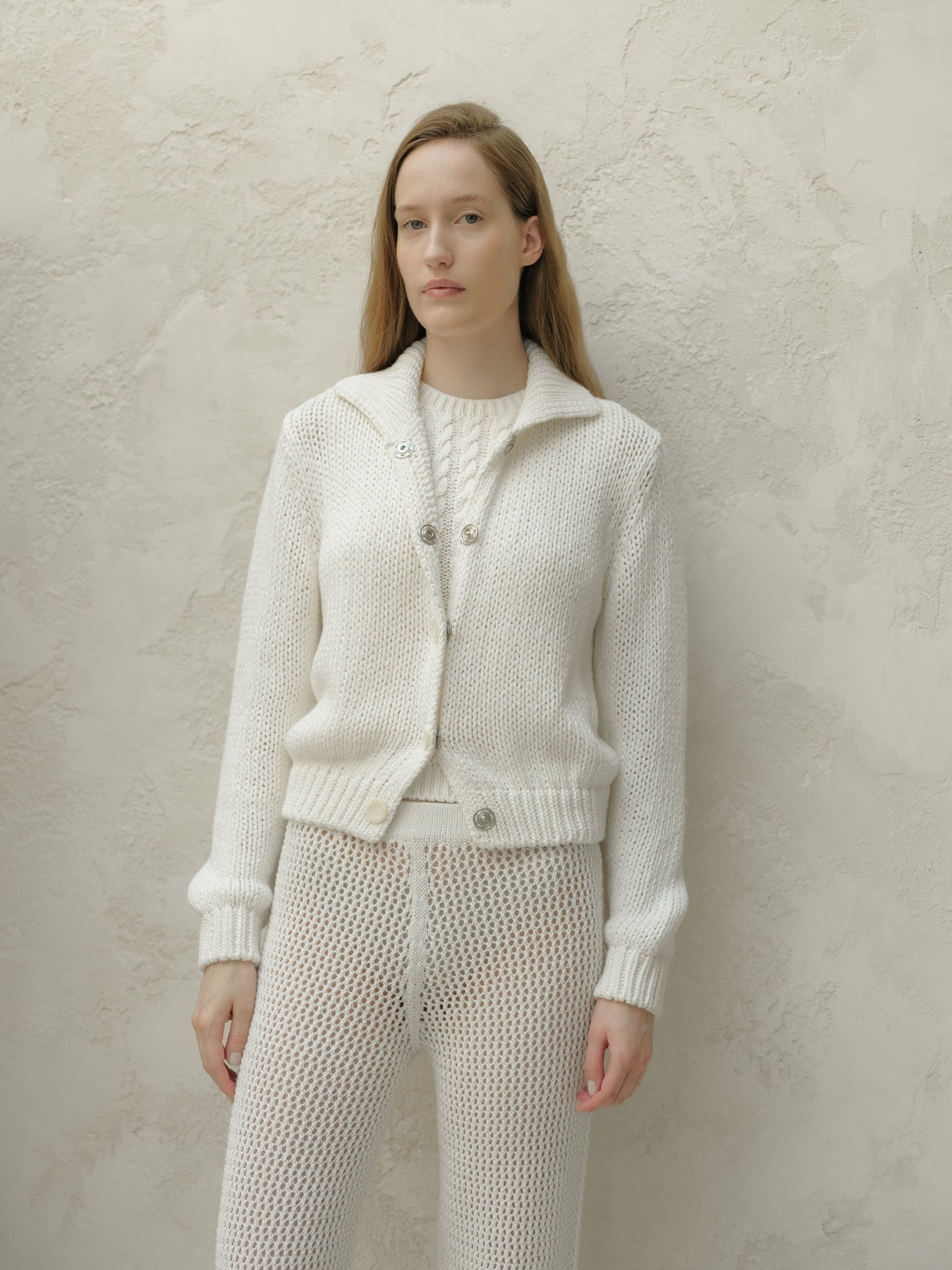 Front view of a model wearing a white textured knit bomber jacket with a collar and metal buttons.