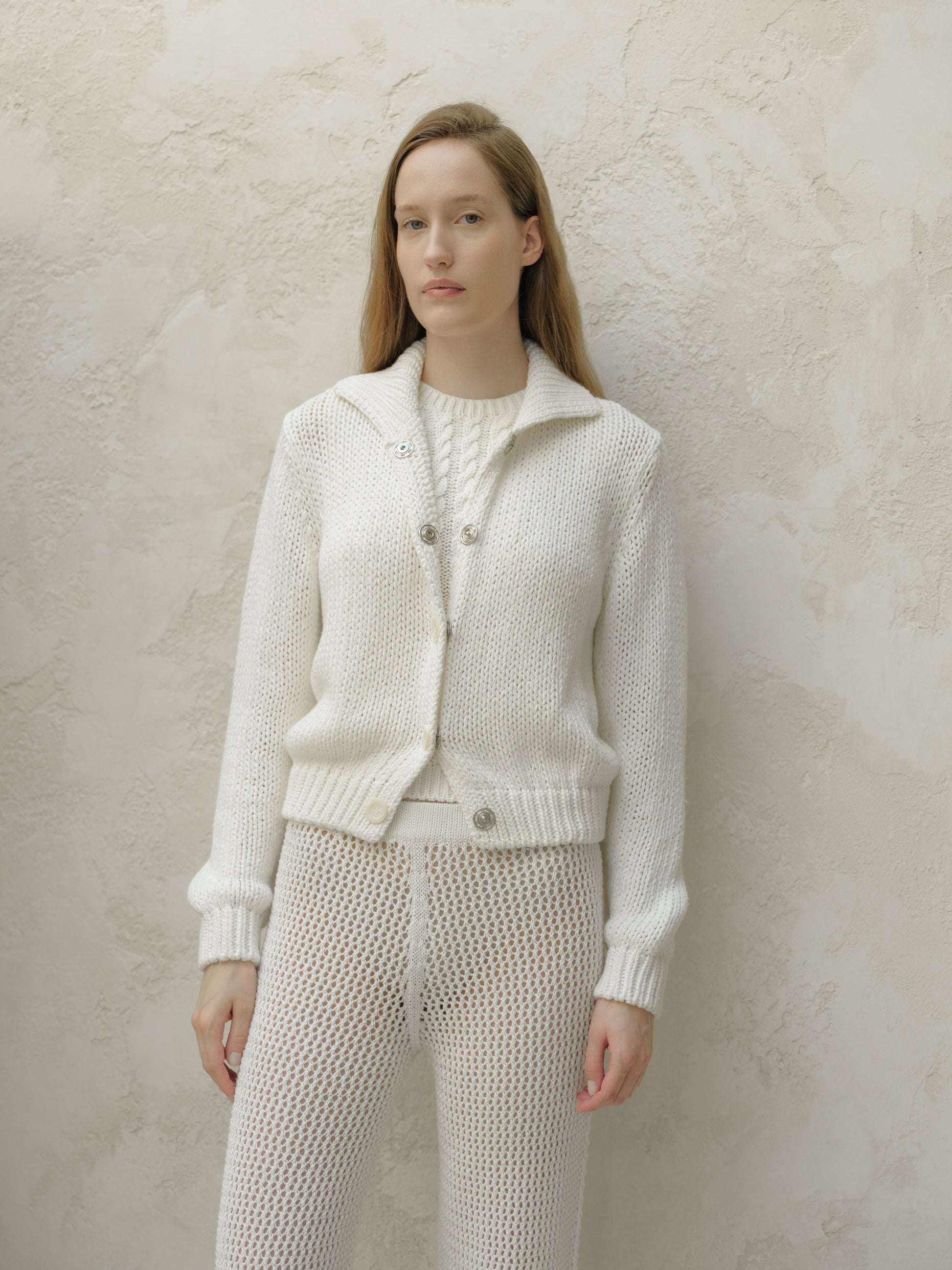 Front view of a model wearing a white textured knit bomber jacket with a collar and metal buttons.