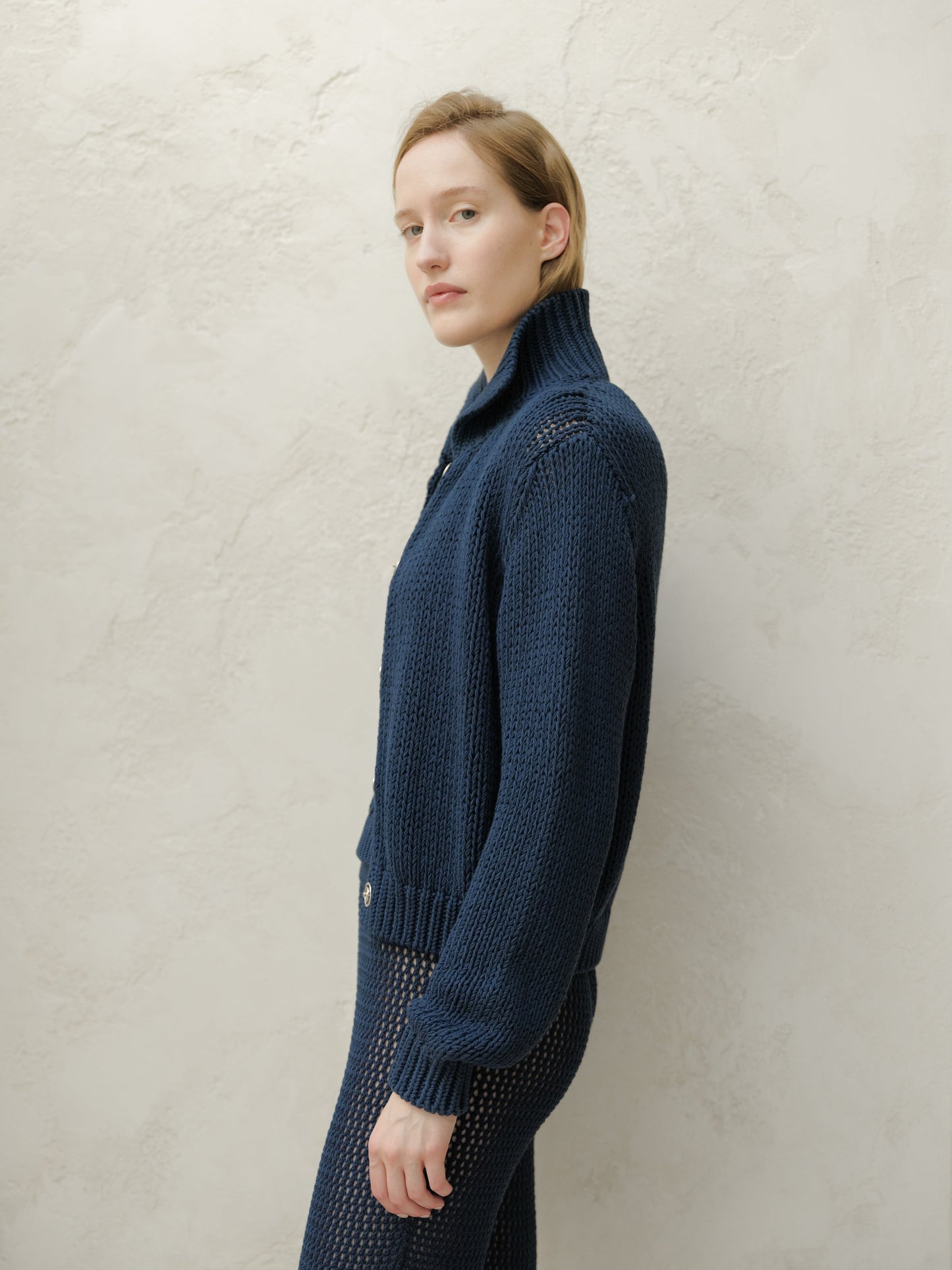 Side profile of a model wearing a navy Fine Cotton Bomber Jacket with a chunky knit texture