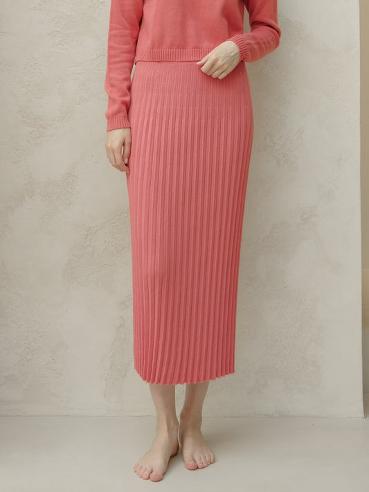 Person wearing a pink ribbed knit skirt and sweater against a beige background