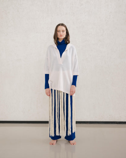 Model wears a pale cream Extra Fine Merino Wool Maxi Polo with a royal blue underlayer and a long fringe skirt.