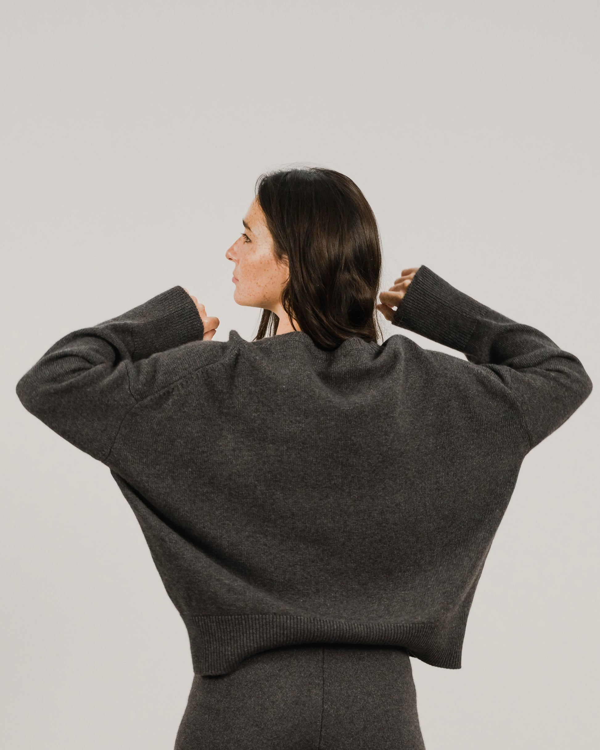 Back view of a model wearing an oversized charcoal cashmere mix crewneck sweater