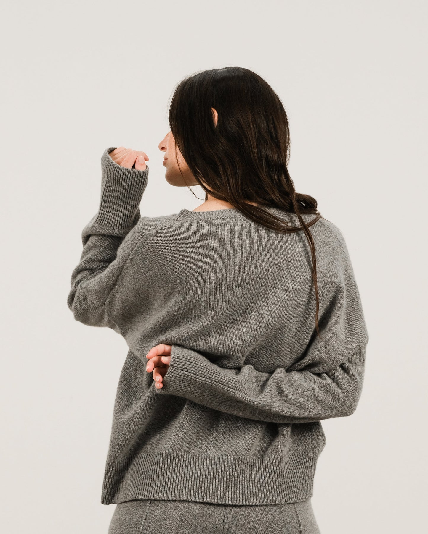 Back view of a model wearing a grey cashmere mix crewneck sweater with a relaxed fit.