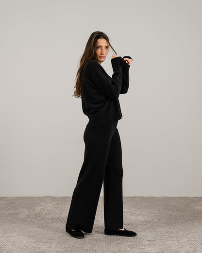 Full body side view of a woman in a black cashmere mix crewneck sweater with wide-leg pants