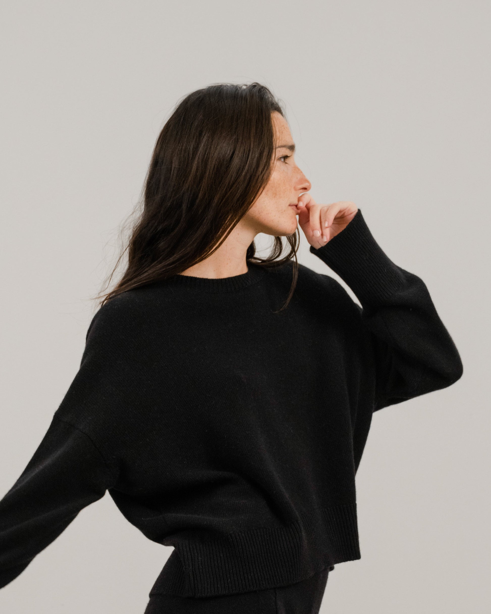 Side profile of a woman wearing a black cropped cashmere mix crewneck sweater
