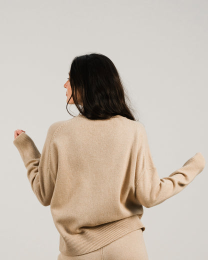 Back view of a beige cashmere mix crewneck sweater on a model