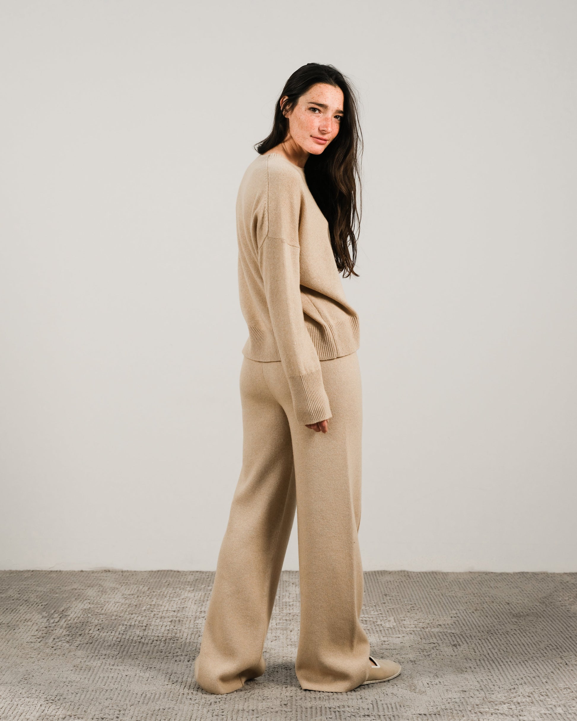 Beige cashmere mix crewneck sweater with matching wide-leg pants on a model shown in a side view