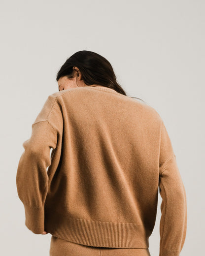 Back view of a woman in camel cashmere mix crewneck sweater and matching pants.