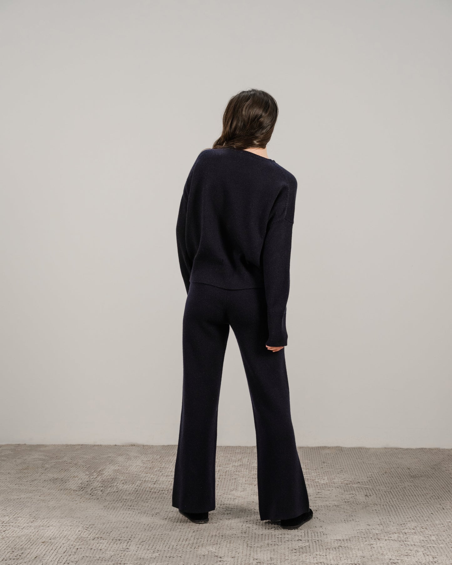 Back view of a model wearing navy cashmere mix crewneck sweater with matching wide-leg pants