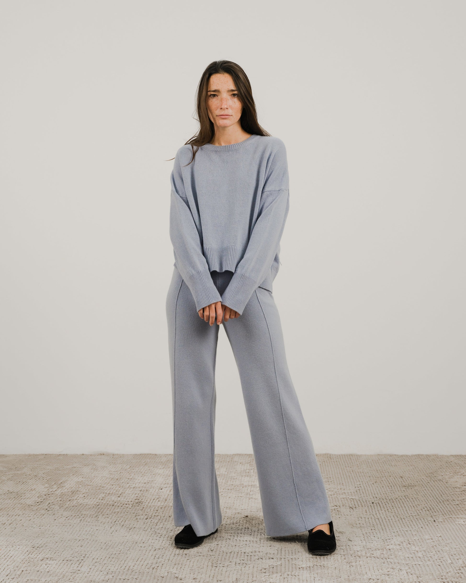 Full-body front view of a model wearing a light blue cashmere mix crewneck sweater with matching wide-leg pants
