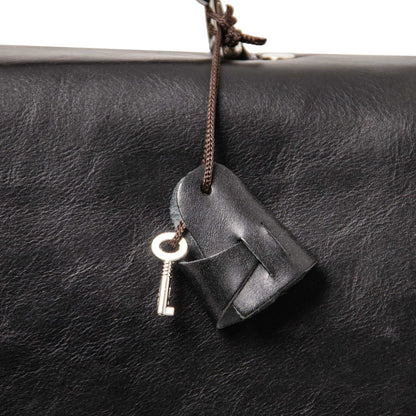 Alessandria matte leather laptop briefcase close-up with a leather tag and key on a brown cord