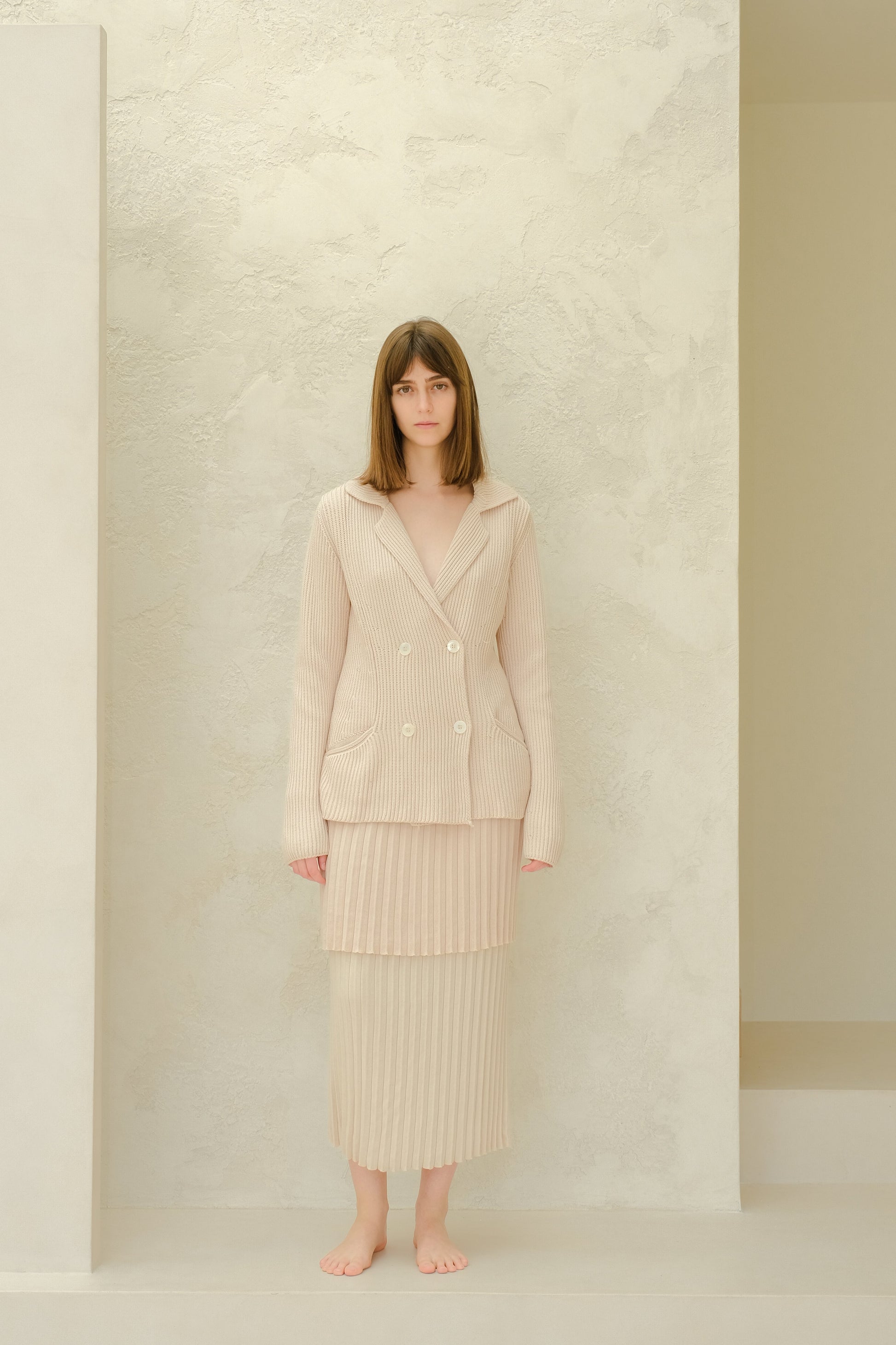 Model wearing a beige Fine Cotton Plissé Long Skirt with a matching double-breasted knit blazer