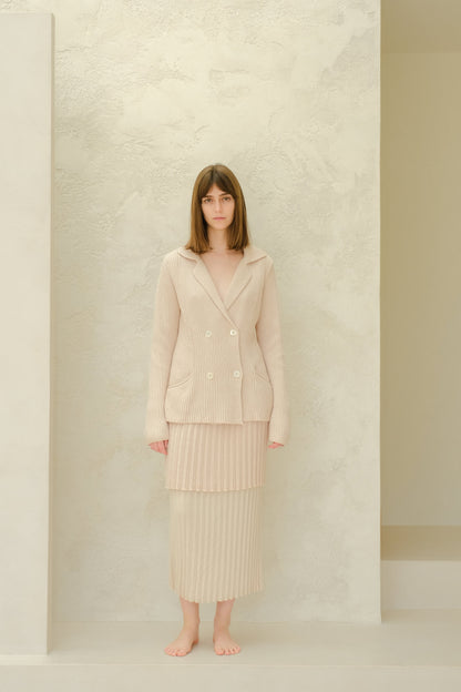Model wearing a beige Fine Cotton Plissé Long Skirt with a matching double-breasted knit blazer