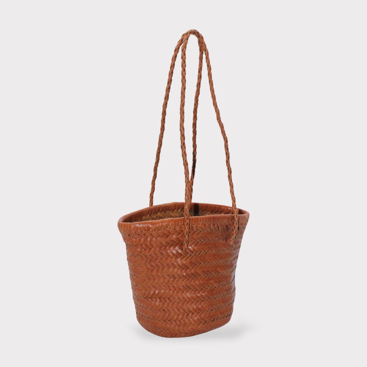 Carmel hand woven brown leather shoulder bucket bag shown in side view with braided handles.
