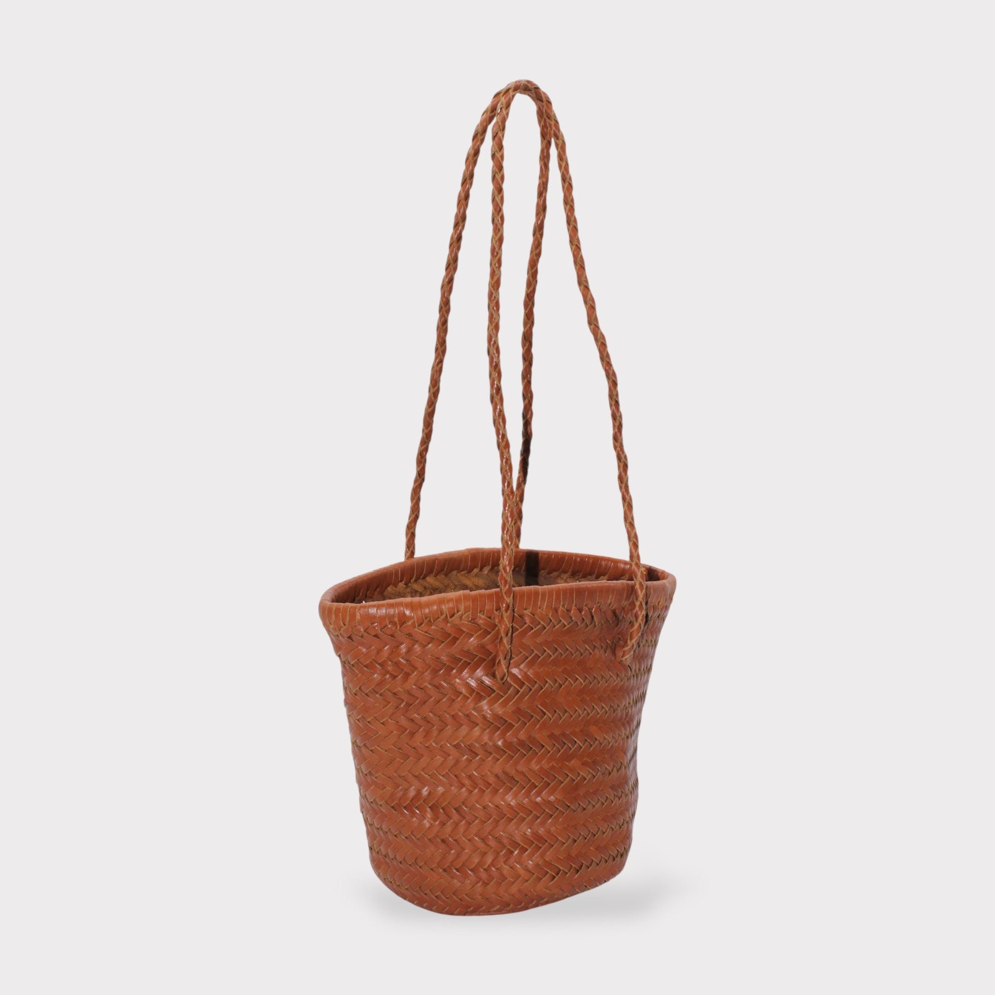 Carmel hand woven brown leather shoulder bucket bag shown in side view with braided handles.