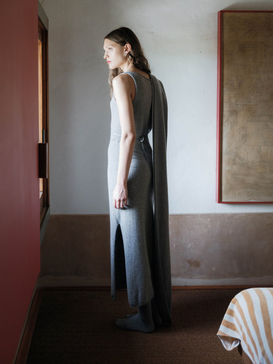 Model in a grey cashmere blend boat neck sleeveless dress with a draped back panel