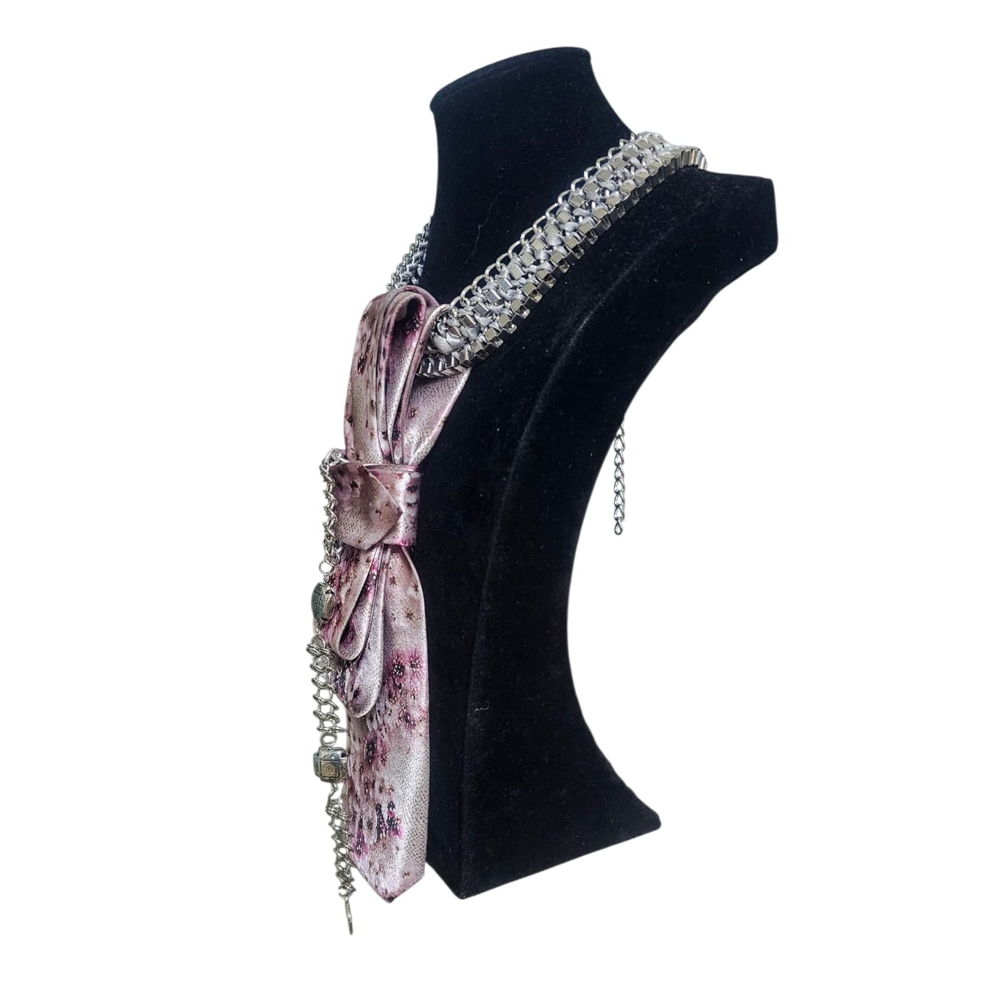 Shiny silver chain necklace paired with a pink floral silk tie draped on a display bust.
