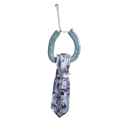 Close-up of pink floral silk tie with bow and dangling chains on a display bust.