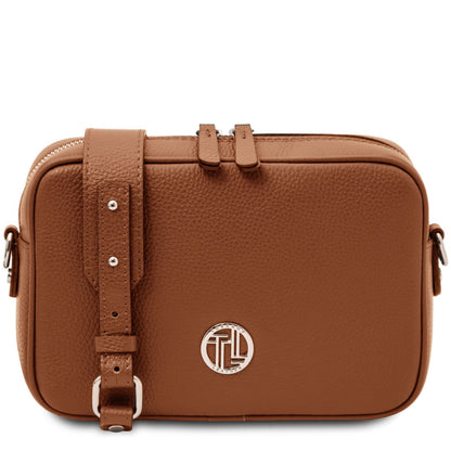 Tan leather shoulder bag with front circular logo plaque and adjustable strap.
