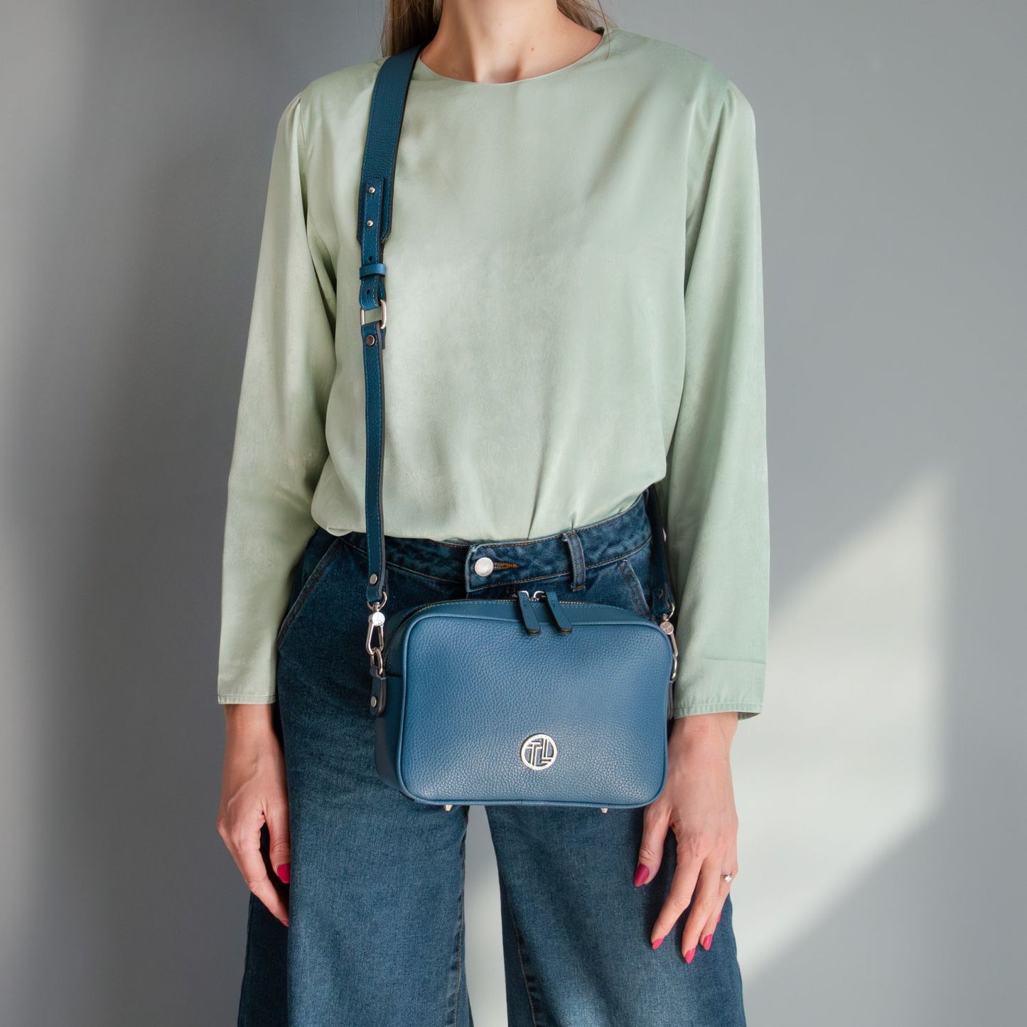 Model wearing Cubetto blue Italian leather shoulder bag with a matching crossbody strap.