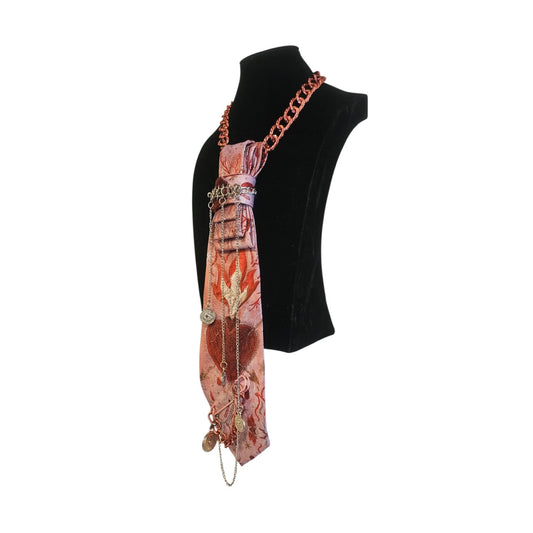 Pink patterned scarf with leaf and heart motifs draped as a tie with multiple hanging charms