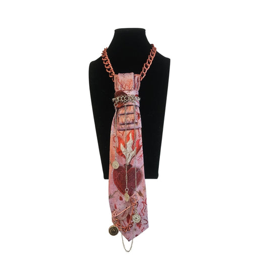 Pink patterned scarf tied as a necklace with a rose gold chain and dangling charms