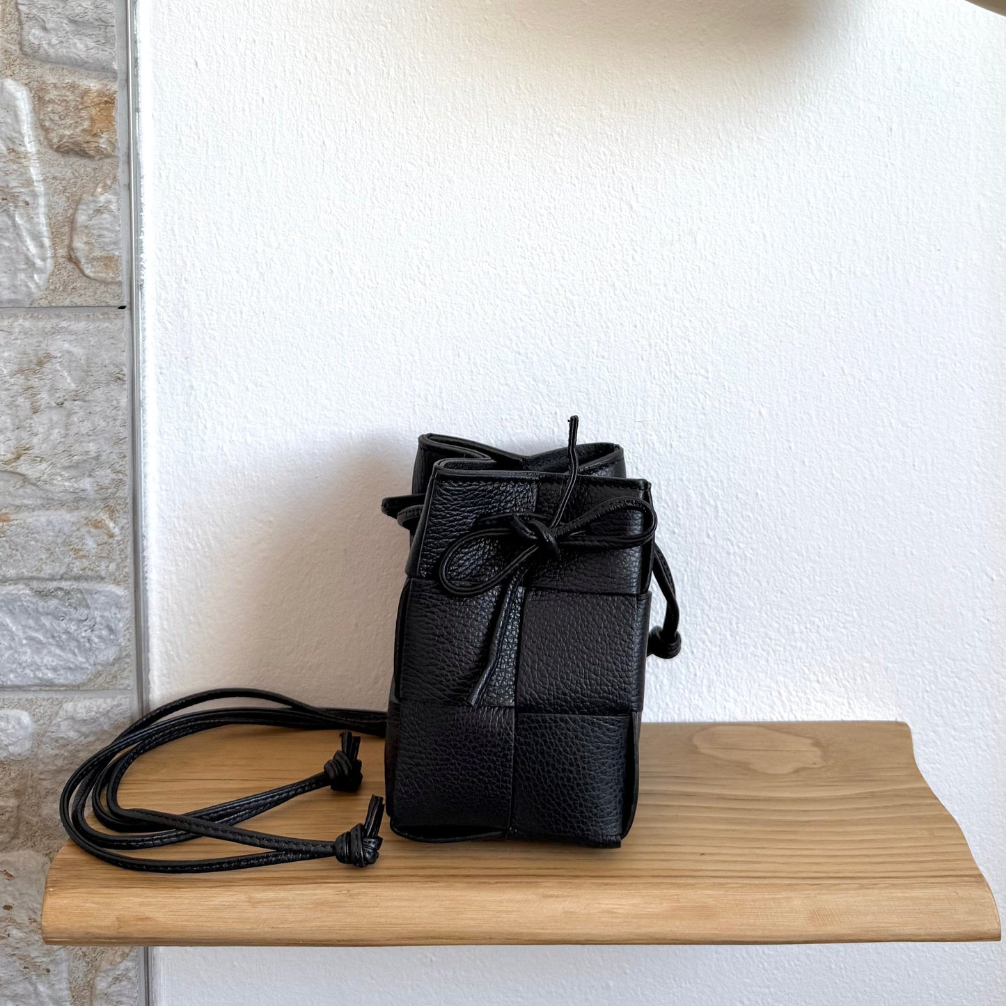 Emi handmade black leather woven crossbody bag with drawstring closure and long strap.