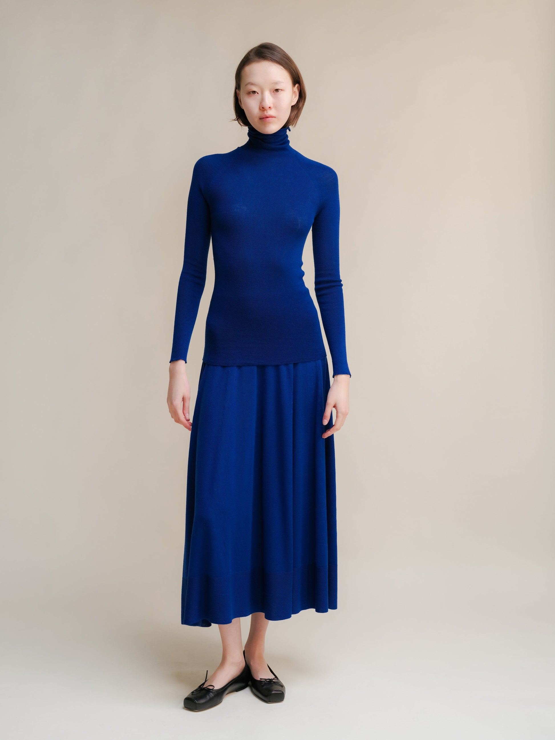 Cobalt blue Extra Fine Merino Wool 3D-Knit A-line skirt worn with a matching turtleneck.