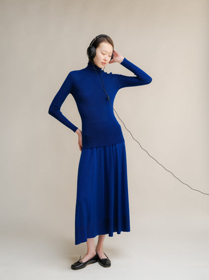 Model wearing cobalt blue merino wool A-line 3D-knit skirt with a matching top and headphones.
