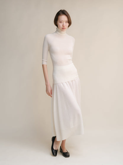 Model wearing a cream turtleneck and cream 3D Knit Extra Fine Merino Wool A-Line skirt