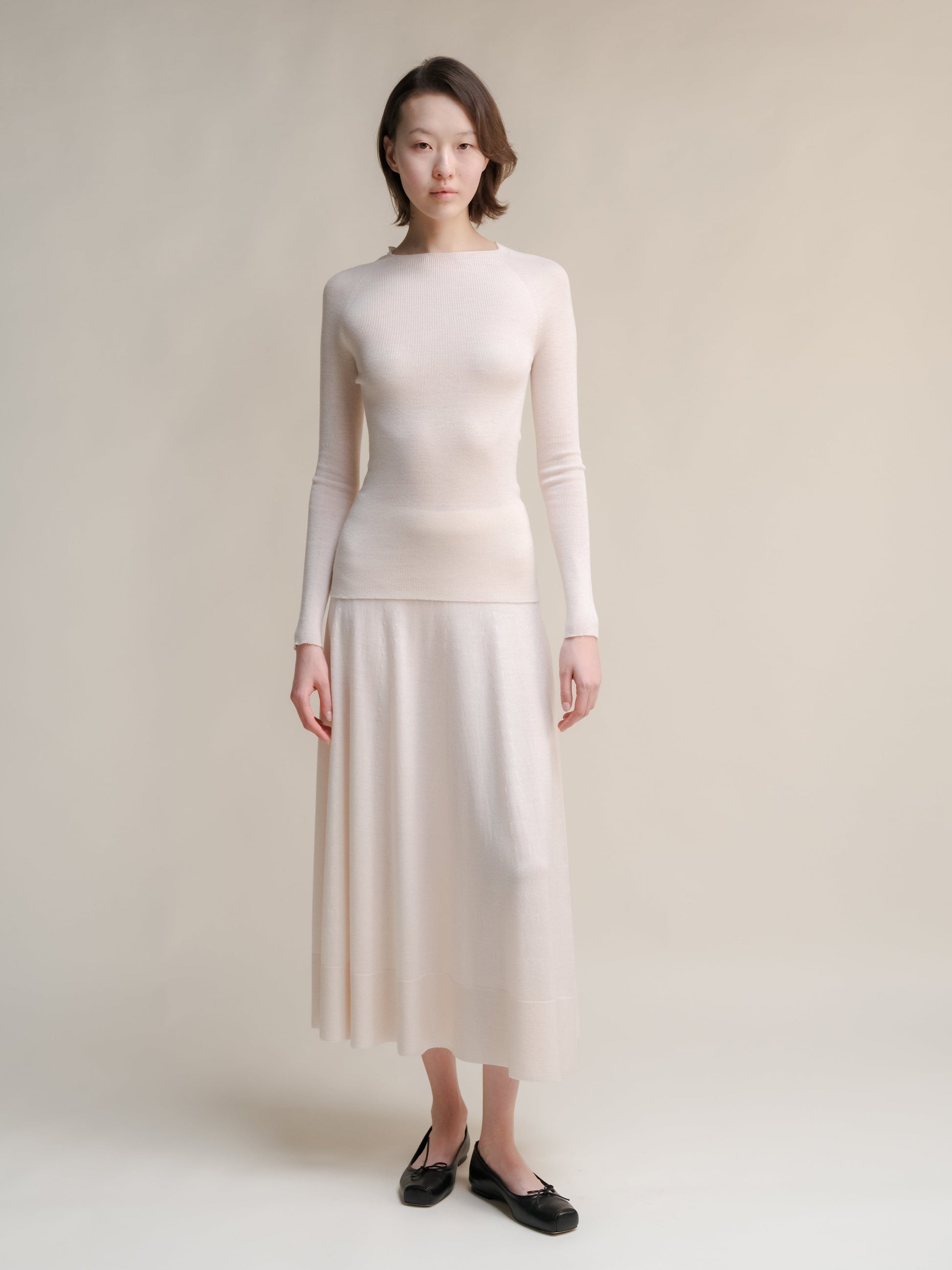 Cream Extra Fine Merino Wool 3D-Knit A-line skirt paired with a matching knit turtleneck sweater.