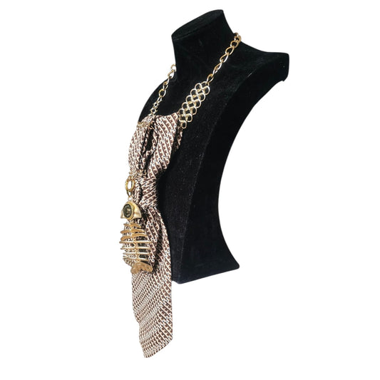 Gold tone chain necklace with a beige patterned tie pendant displayed on a black bust