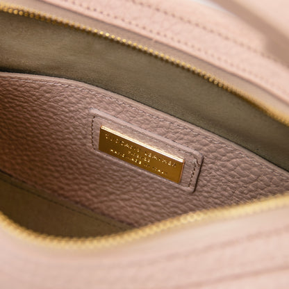 Close up of soft pink pebbled leather interior with a gold metal nameplate on a Hoblò hobo bag