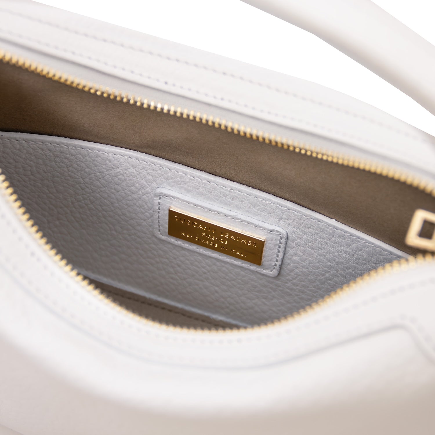 Interior view of white Hoblò soft leather hobo bag showing light grey lining and a gold plate plaque.
