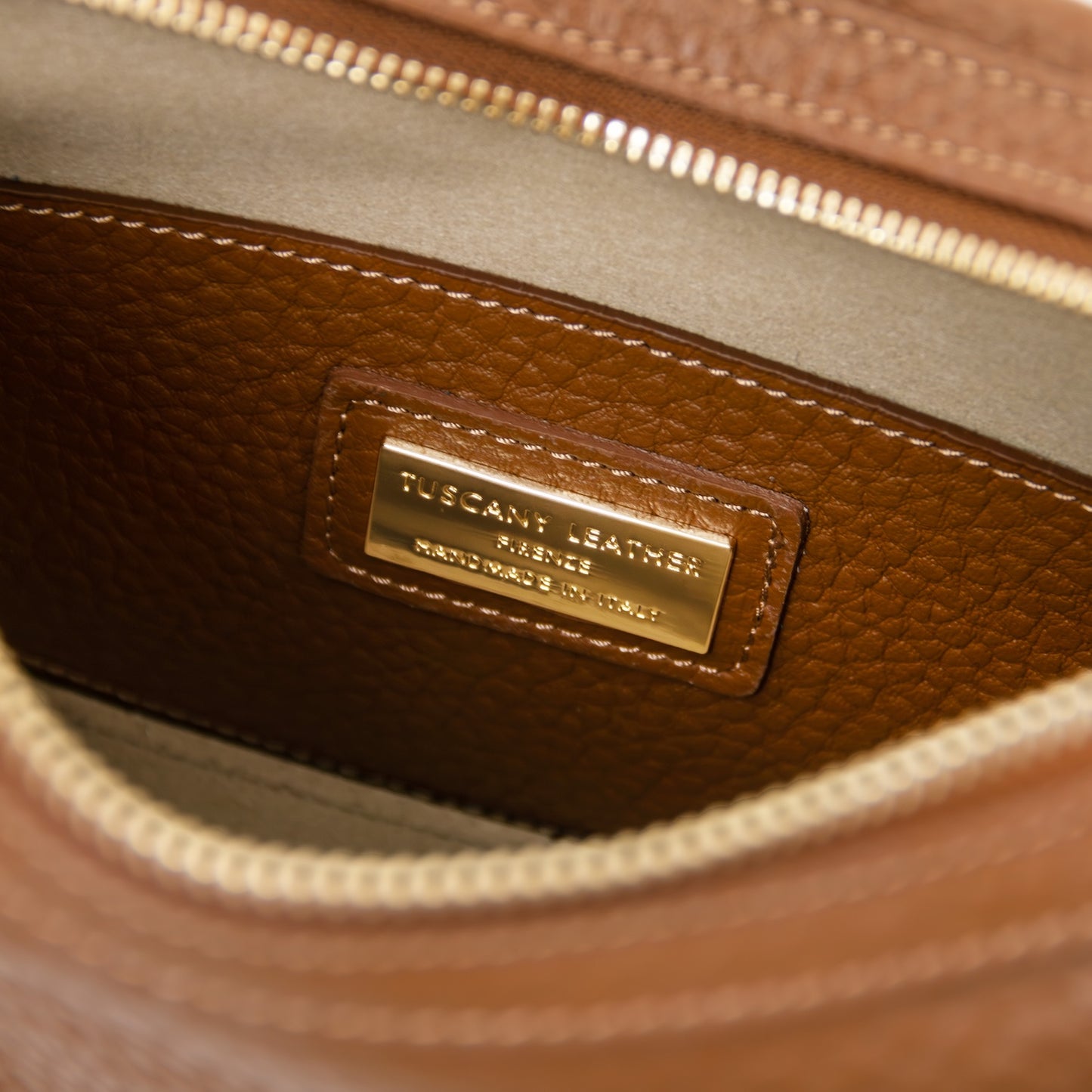 Close-up of tan pebbled leather interior with a gold metal nameplate stitched on a patch