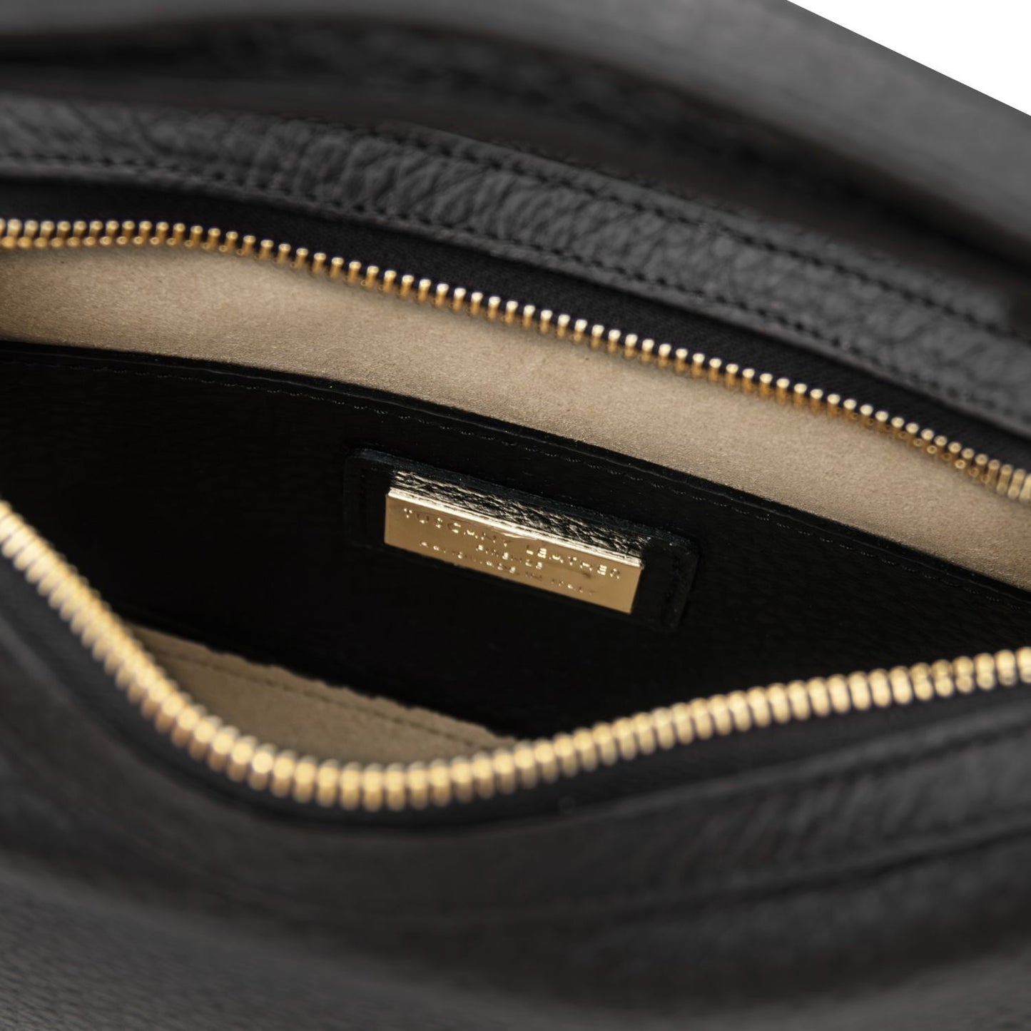 Interior close up of the black Hoblò bag showing the gold zipper and a gold logo plaque on the lining