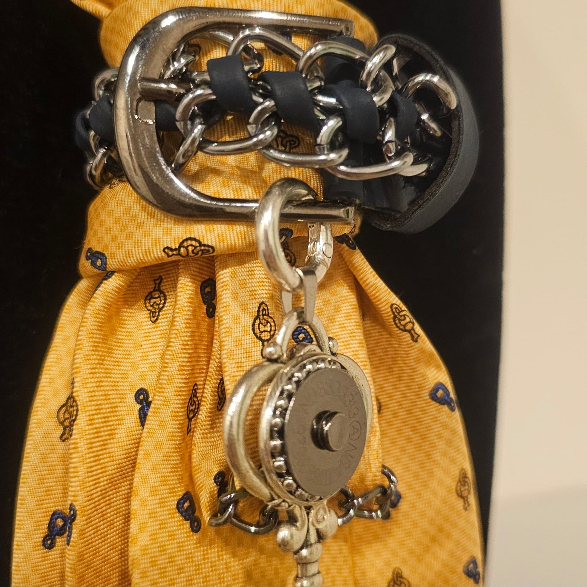 Close-up of I can and I will 4-in-1 Jeweled Tie with a silver chain wrapped around a yellow patterned tie and a hanging charm.