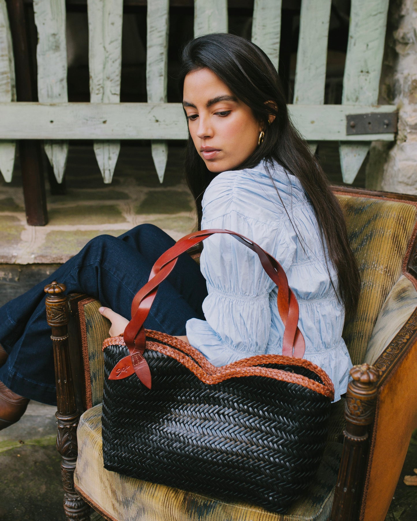Léafa - Handwoven Leather Shoulder Bag | Brown & Black showcasing a woven black leather body with brown leather handles resting on a chair.